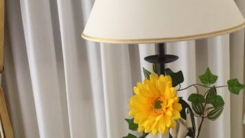 A lamp with a white shade and a floral arrangement on a wooden table.