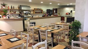 A restaurant with wooden tables and chairs, a bar area, and shelves with bottles and condiments. - Albergo Italia (Fossalta di Piave)