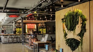 A modern hotel lobby with a reception desk, bar area, and a large wall-mounted plant. - DogHouse Columbus (Canal Winchester)