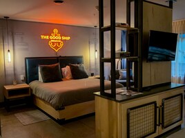 Una habitación de hotel moderna con cama, televisión, escritorio y un letrero de neón en la pared.