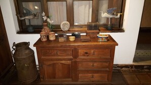 Une commode en bois avec de nombreux tiroirs, une fenêtre agrémentée d’objets décoratifs et un récipient en métal.
