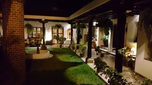 A courtyard with a fountain, potted plants, and a brick wall. - Hotel La Casa de Don Pedro (Antigua Guatemala)