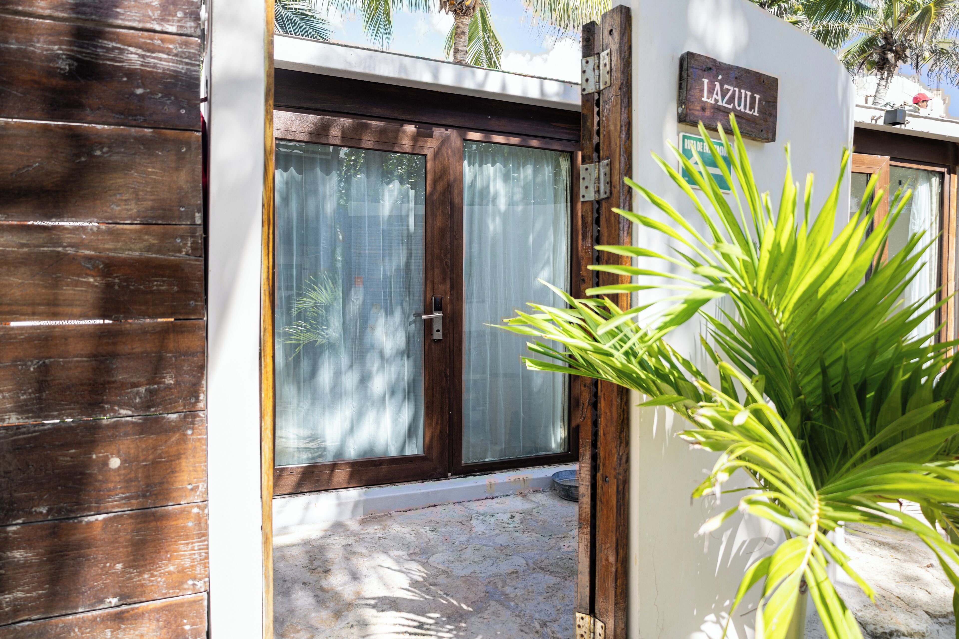A wooden door with a sign reading "LAZULI" and a potted plant in the foreground.