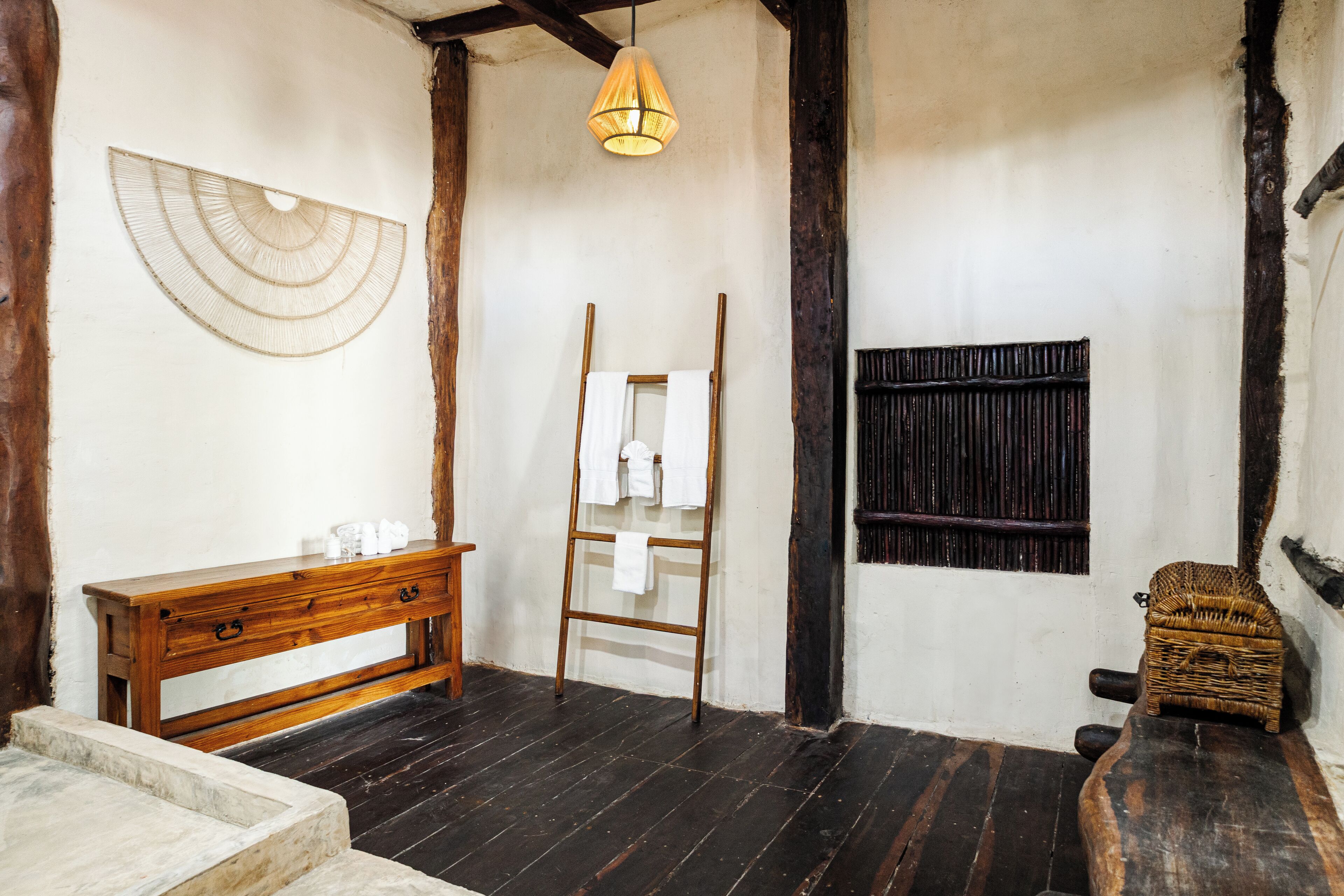 A rustic bathroom with a wooden bench, a wooden ladder, a hanging light fixture, and a woven basket.