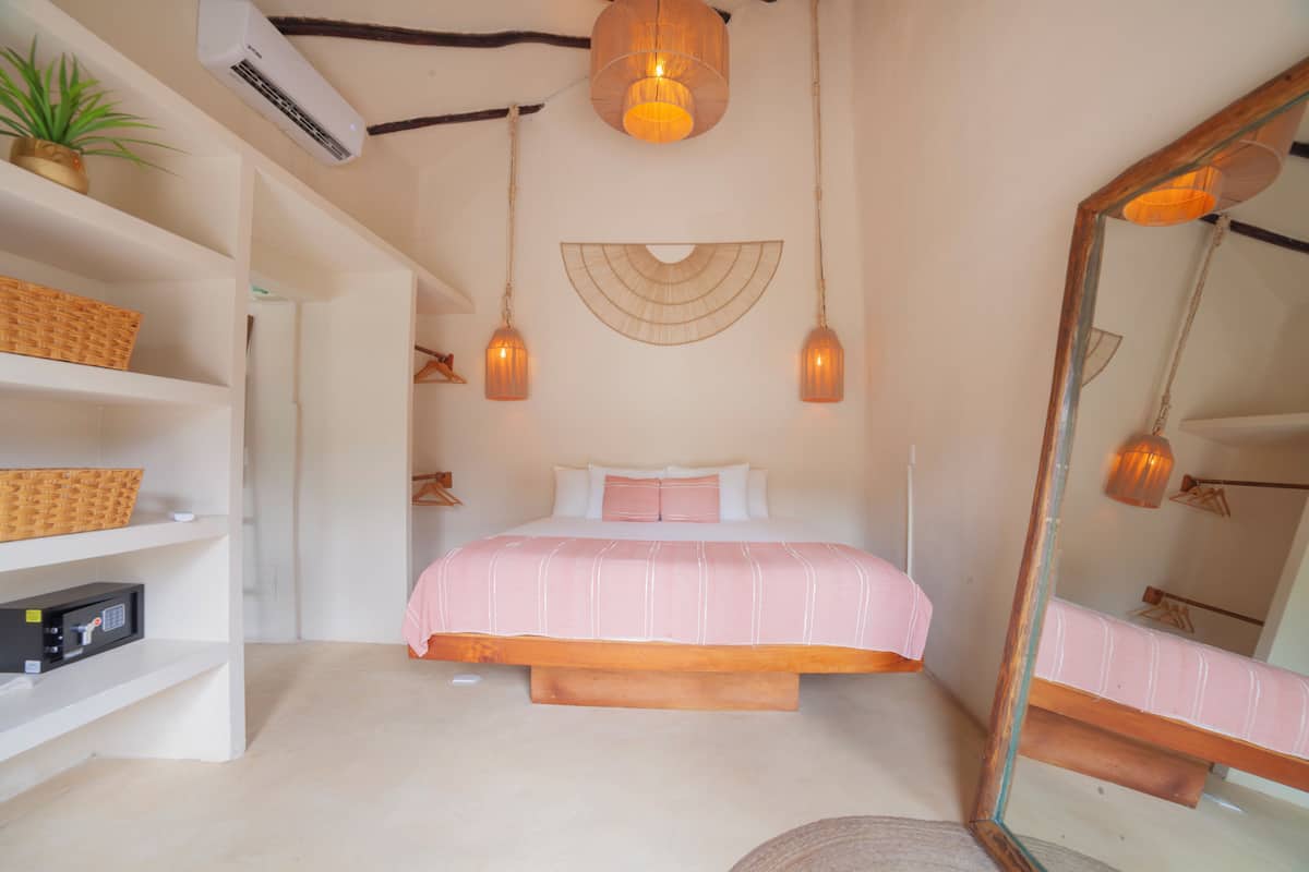 Un dormitorio con cama, estanterías, espejo e iluminación colgante.