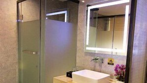 A modern bathroom with a glass shower enclosure, a white sink, and a mirror with integrated lighting. - U-hotel (Shenzhen)