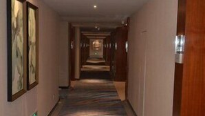 A hotel hallway with a patterned carpet, framed artwork on the walls, and wooden doors. - U-hotel (Shenzhen)