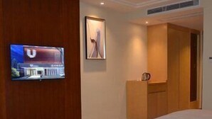 A hotel room with two beds, a TV mounted on the wall, and a framed picture above the bed. - U-hotel (Shenzhen)