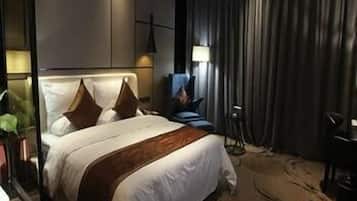 A modern hotel room with a large bed, a desk, and a chair.