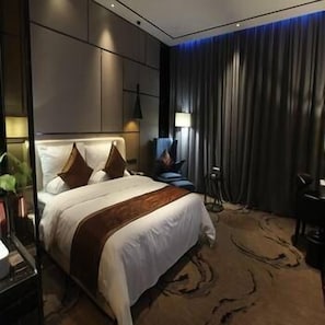 A modern hotel room with a large bed, a desk, and a chair. - Banshan Hotel (Qiandongnan)
