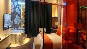 Habitación de hotel con cama, escritorio, silla, televisor y baño.