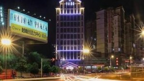 Un hotel de varios pisos con un letrero iluminado y llamativo en la entrada.