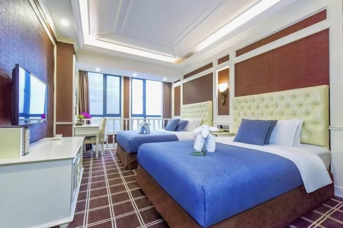 A hotel room with two beds, a desk, and a television.