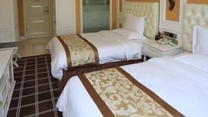 A hotel room with two beds, a nightstand, a lamp, and a window with blinds.