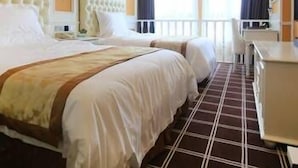 A hotel room with a large bed, a desk, and a TV.