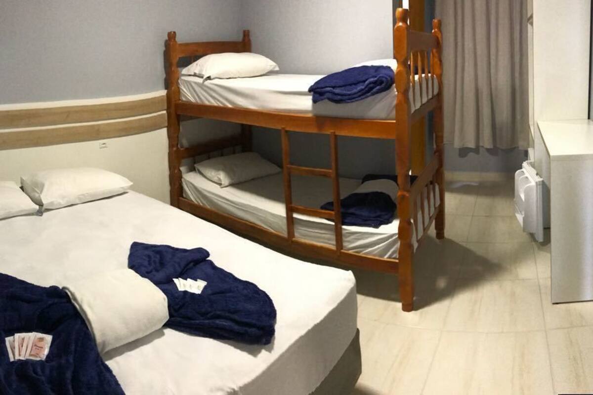 A room with a single bed, a bunk bed, and a small kitchenette.