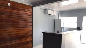 Una cocina moderna con un muro decorado en madera, encimera negra y ventana que proporciona luz natural.