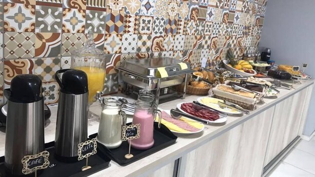 Montaje de bufé con diversos alimentos y bebidas, incluyendo una estación de café con dispensadores identificados.