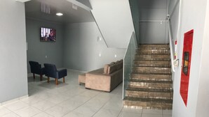 Un vestíbulo amplio con piso de baldosas, una escalera y un televisor montado en la pared.