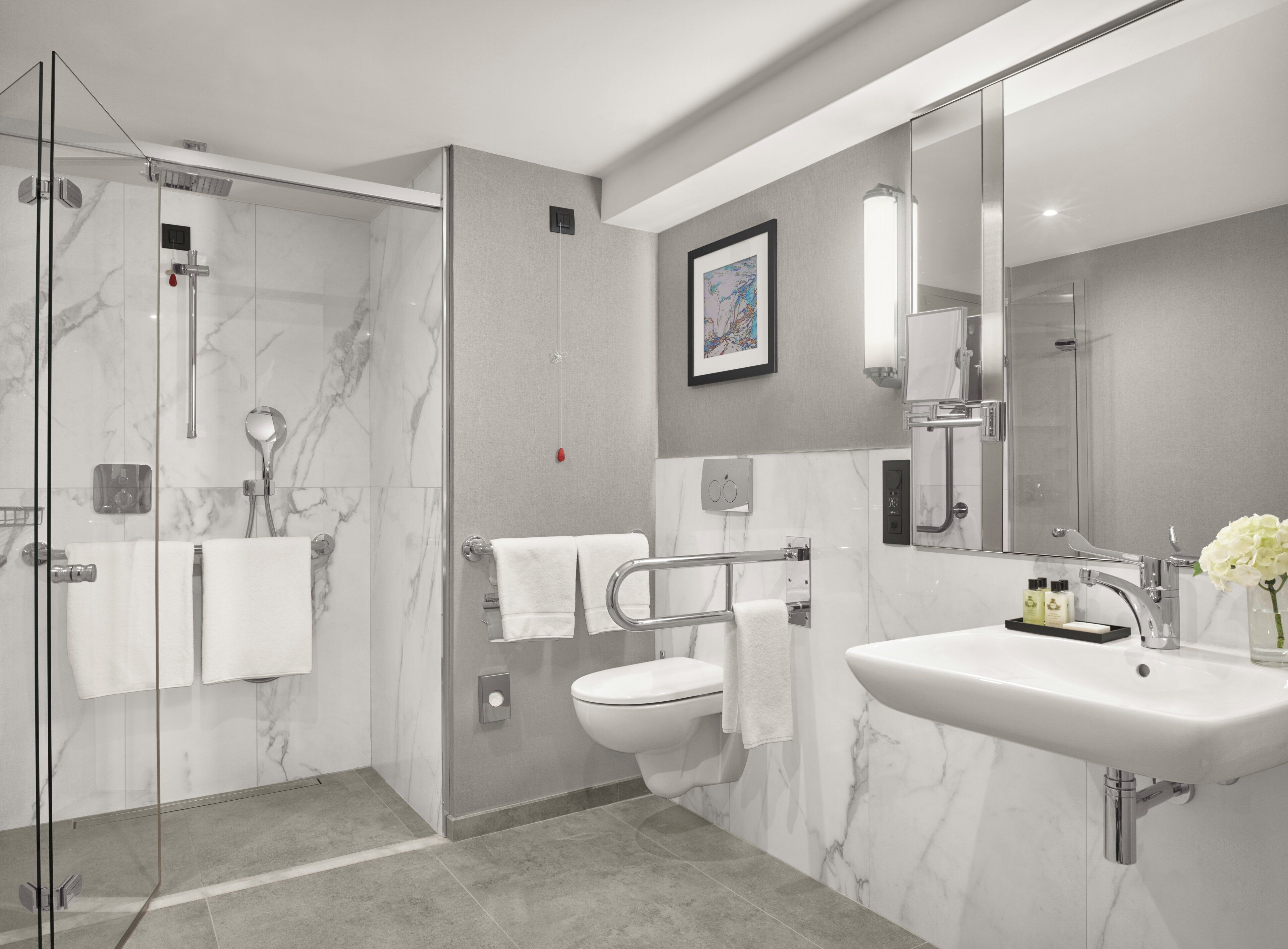 A modern bathroom with a glass-enclosed shower, a white toilet, and a large sink with a mirror.