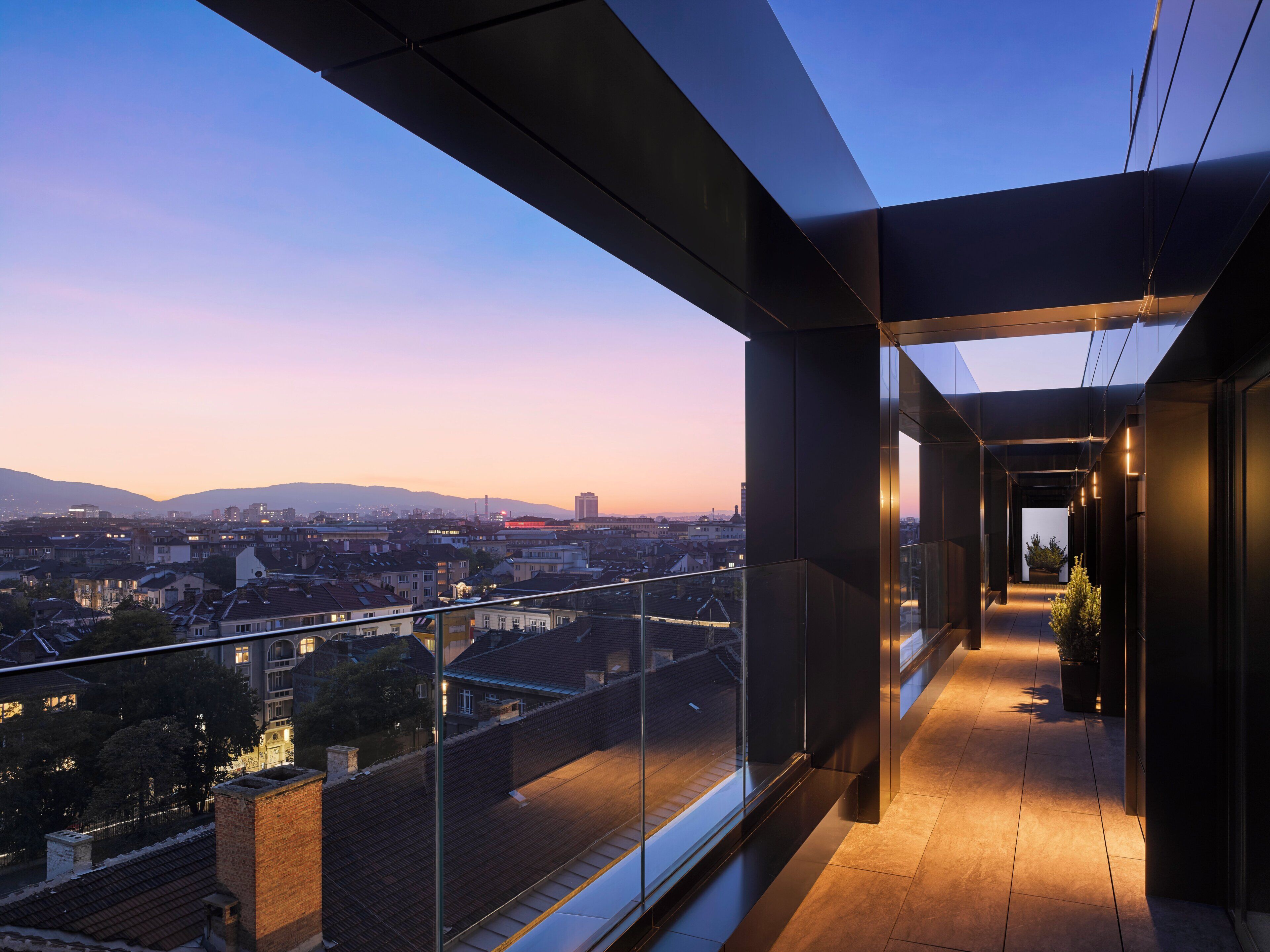 A modern balcony with a city view at dusk.