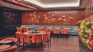 A restaurant with wooden panel walls, orange chairs, and tables set for dining.
