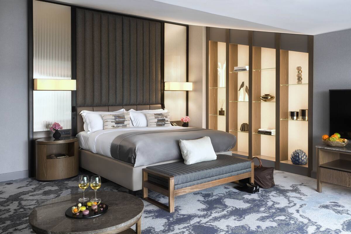 Una habitación de hotel moderna con una cama grande, mesitas de noche, una zona de estar y un televisor.