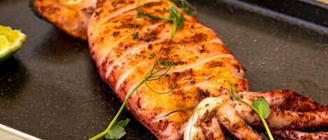 Plato con pulpo a la parrilla, hierbas y presentación elegante.