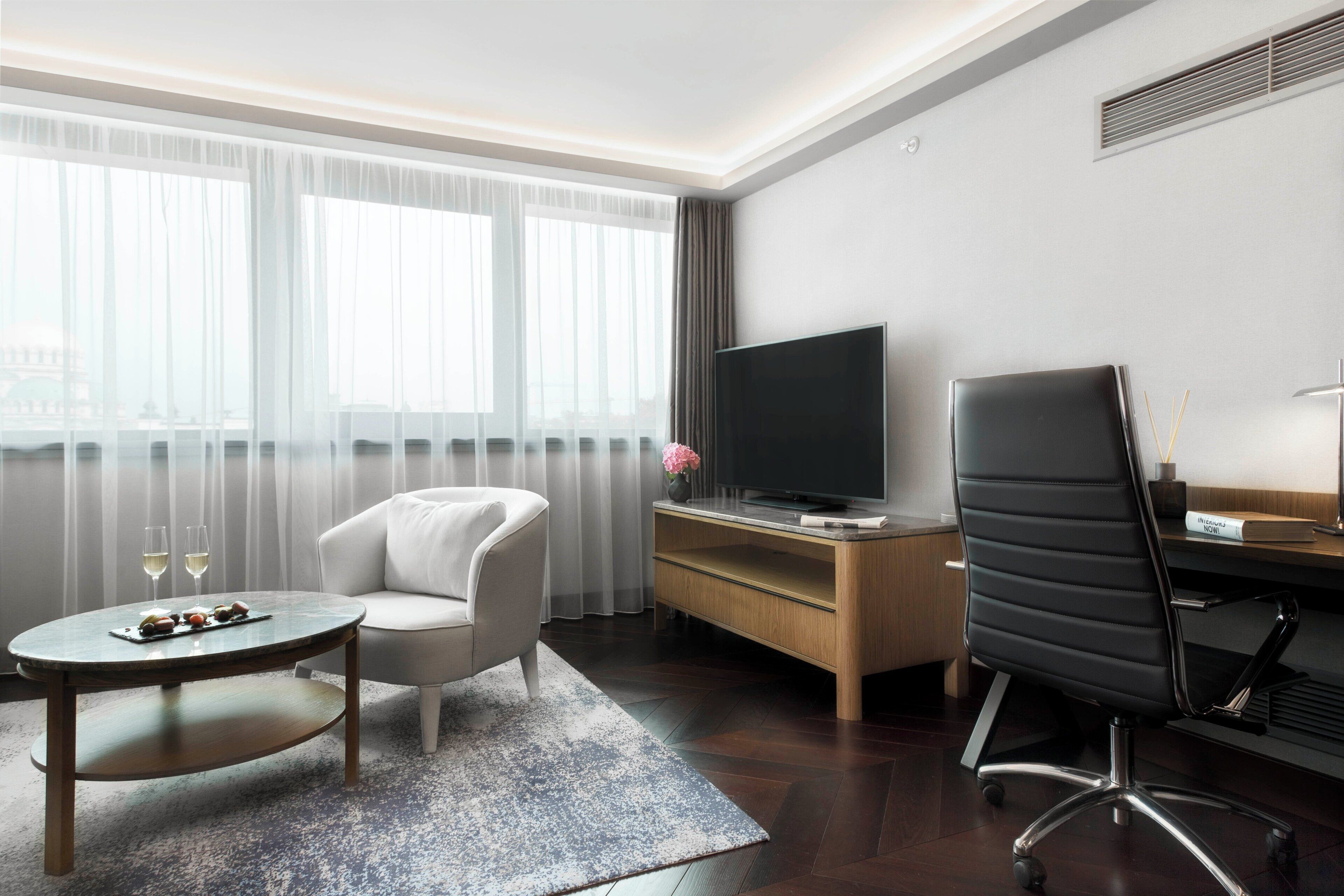 Une chambre d’hôtel équipée d’une télévision à écran plat, d’un canapé, d’un bureau et d’une chaise.