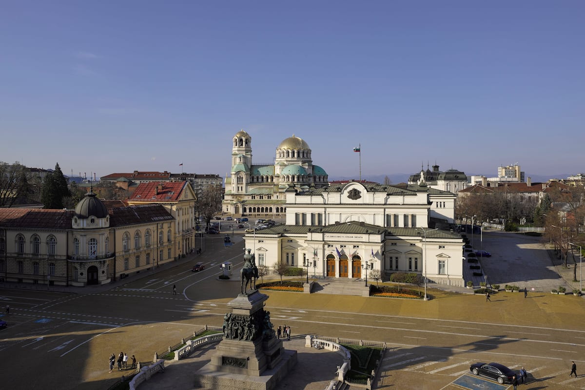 A large, historic building with a prominent dome and a statue in front.