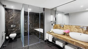 A modern bathroom with a glass-enclosed shower, a toilet, and two sinks with marble countertops.