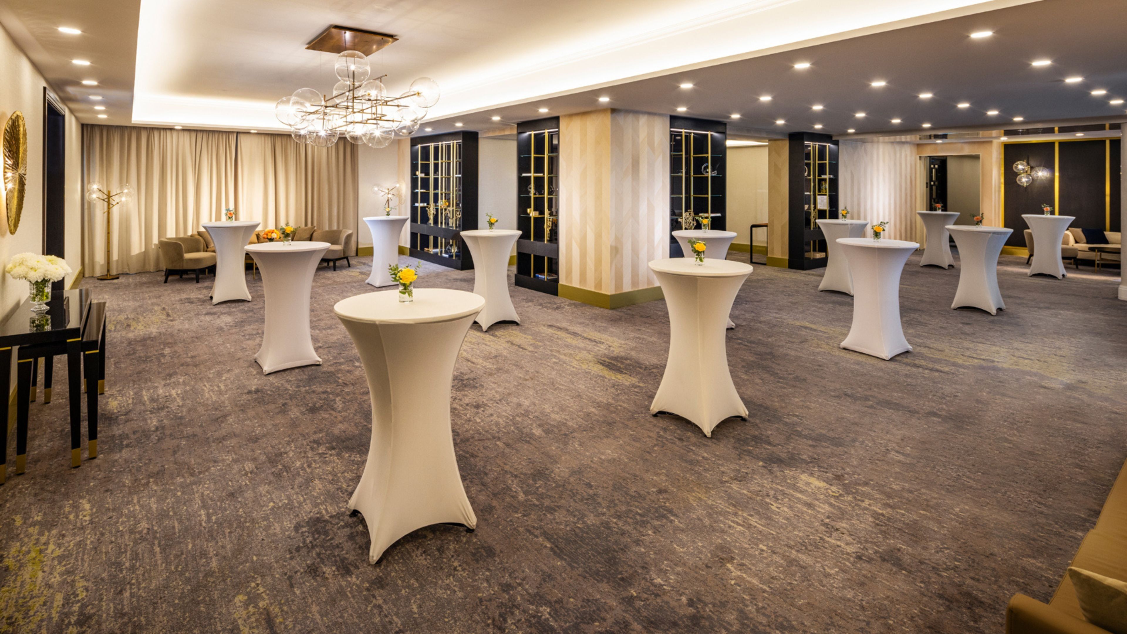 Een hotellobby met ronde tafels, een kroonluchter en een vloerbedekking.