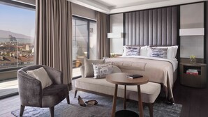 A modern hotel room with a large bed, a sofa, a small round table, and a view of a cityscape. - InterContinental Sofia by IHG (Sofia)