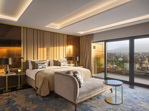 A modern hotel room with a large bed, a sofa, a small table, and a view of the city through large windows. - InterContinental Sofia by IHG (Sofia)