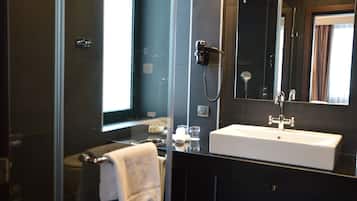 Een moderne badkamer met een glazen douchecabine, een witte wastafel en een grote spiegel.