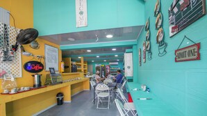 Interior de una cafetería con mostrador, sillas y un panel de menú.