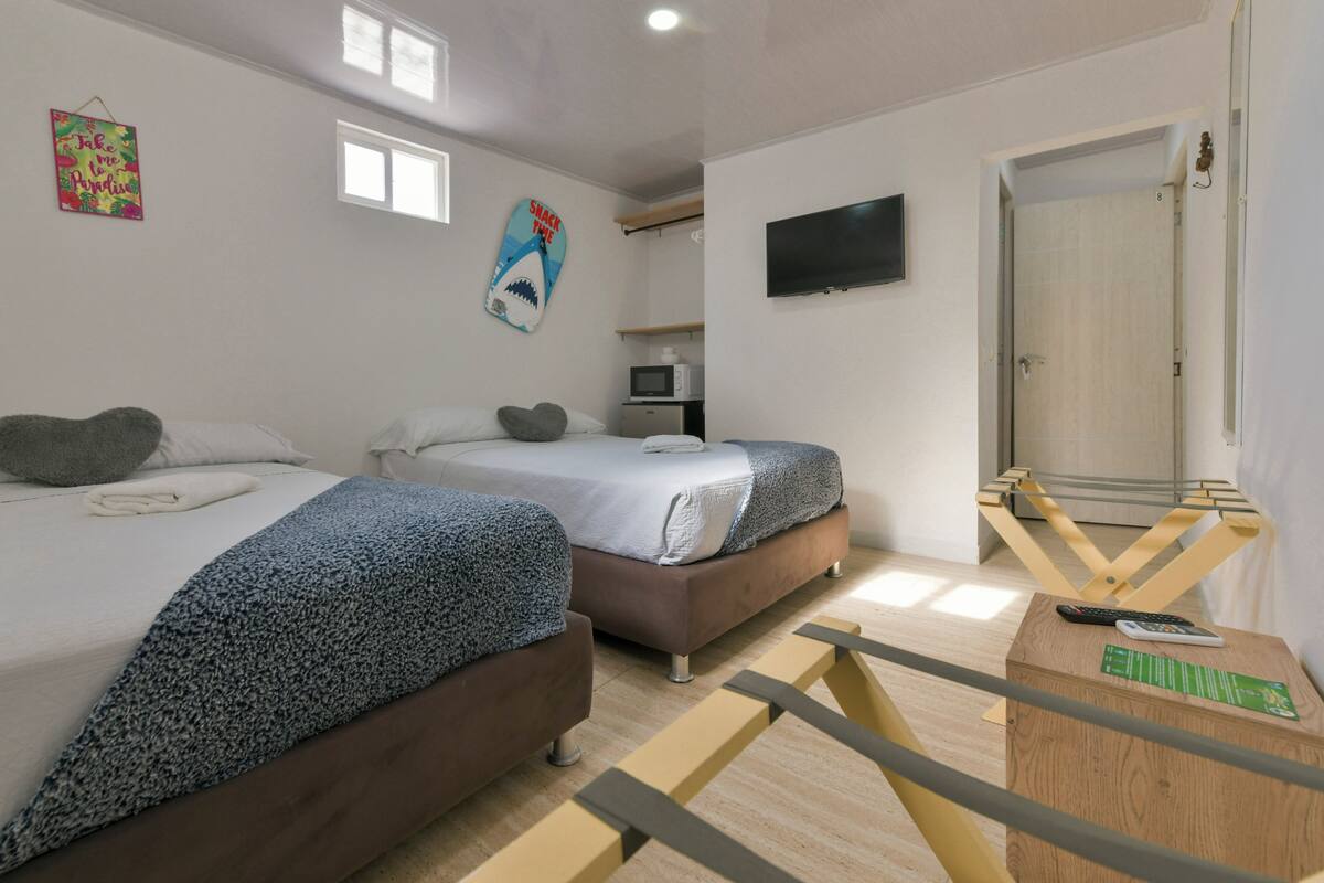 A room with two beds, a TV, a microwave, and a door.