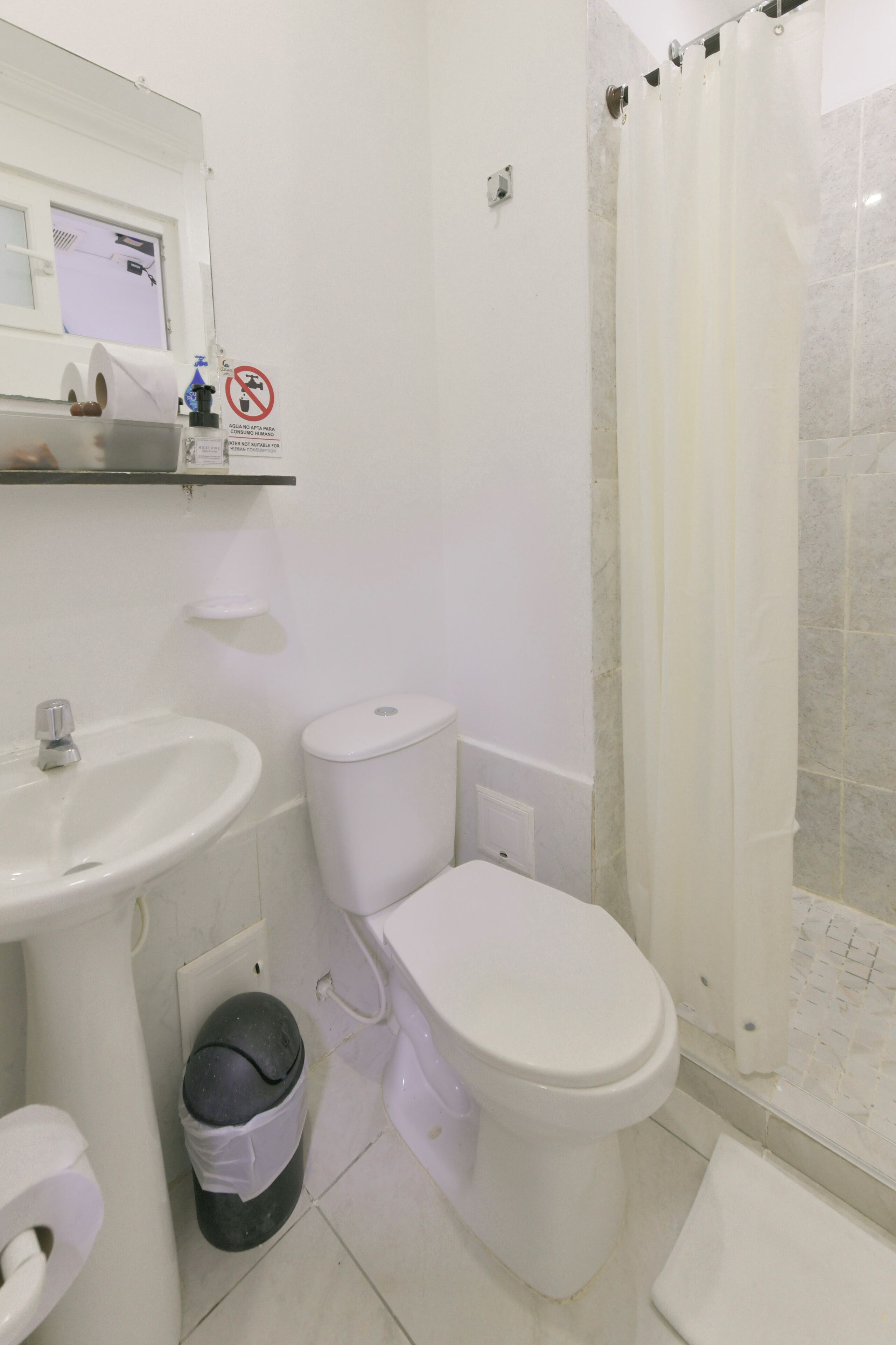 Un baño con inodoro, lavamanos y cortina de ducha.