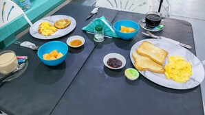 Una mesa de desayuno con platos de huevos, tostadas y fruta, junto con tazas de café y té.