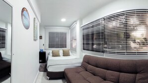 Un dormitorio con una cama, un sofá marrón y un ventanal con persianas.