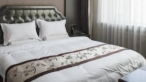 A hotel room with a large bed, a headboard, a nightstand, and a window with curtains. - Banfu Hotel (Harbin)