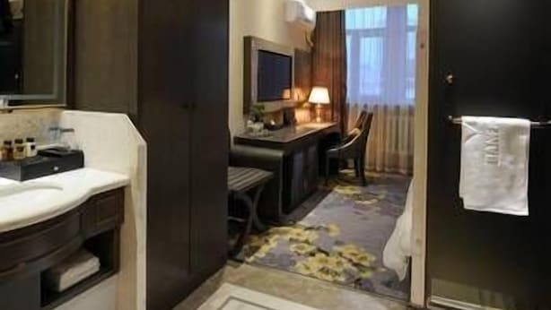 A hotel room with a bathroom, a desk, a chair, and a bed. - Banfu Hotel (Harbin)