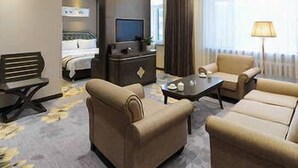 A hotel room with a bed, a desk, a TV, two sofas, and a lamp. - Banfu Hotel (Harbin)