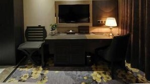 A hotel room with a bed, a desk with a computer, a TV, and a lamp. - Banfu Hotel (Harbin)