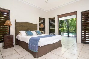 A bedroom with a large bed, two bedside tables, and a view of a garden through the window.