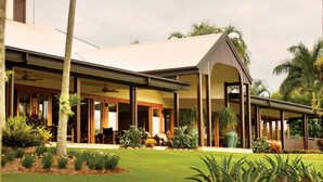 A modern house with a covered patio, large windows, and a well-maintained lawn. - Tranquility By The Course Port Douglas (Craiglie)
