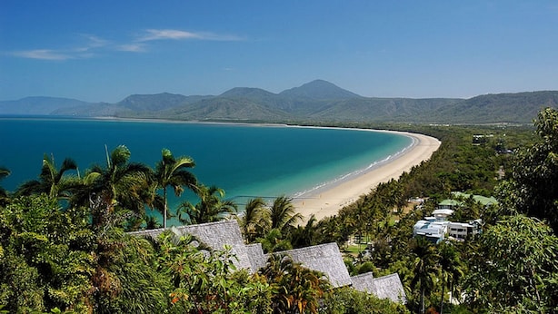 A coastal view with a beach, clear blue water, and mountains in the background. - Tranquility By The Course Port Douglas (Craiglie)