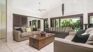 A spacious living room with two sofas, a coffee table, and a ceiling fan. - Tranquility By The Course Port Douglas (Craiglie)