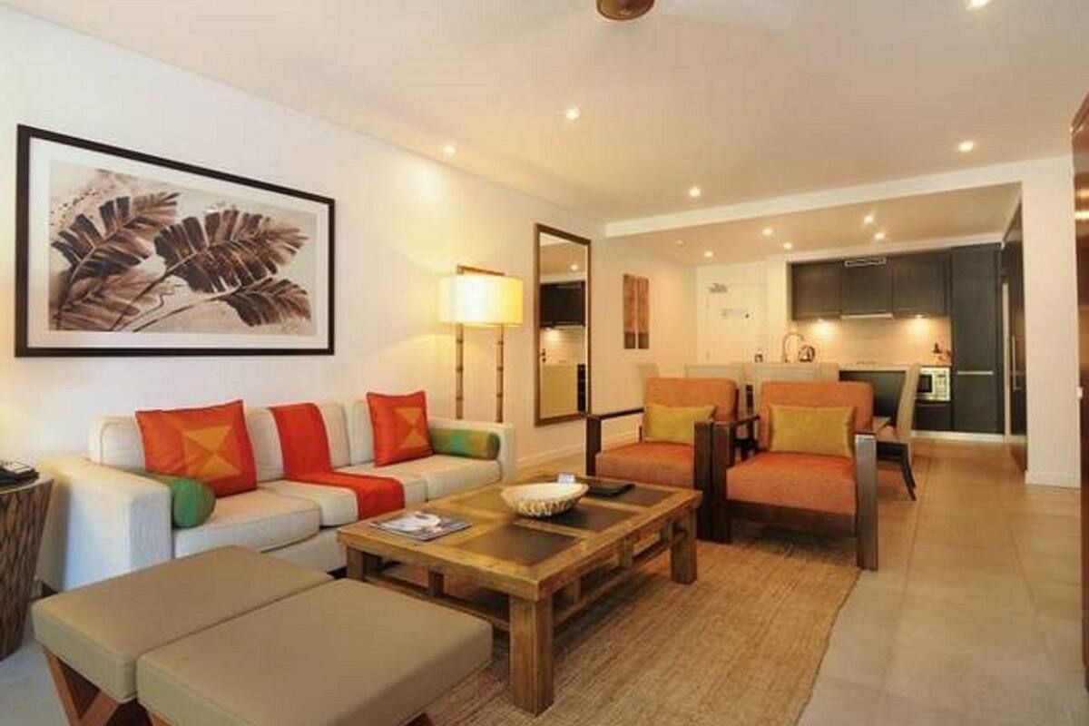 A living room with a sofa, armchairs, a coffee table, and a painting on the wall.