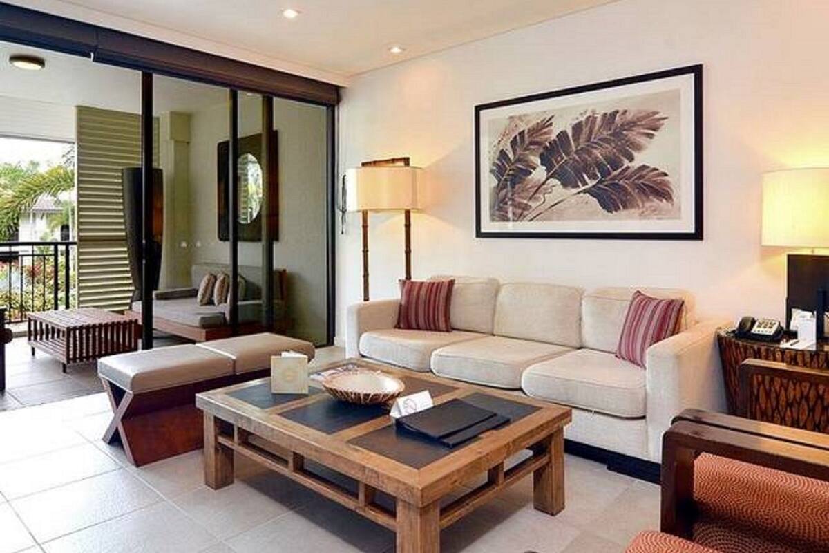 A modern living room with a sofa set, a coffee table, and a large framed artwork on the wall.